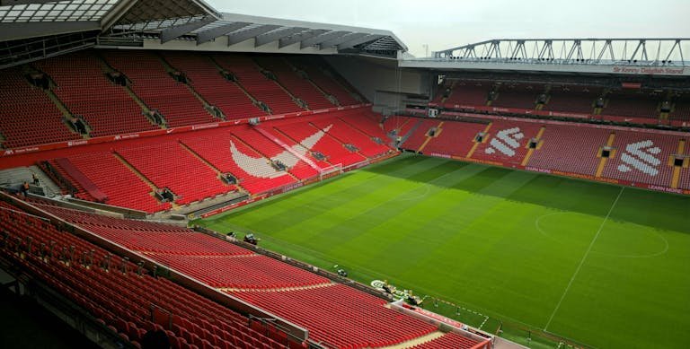 An empty stadium with red seats and green grass