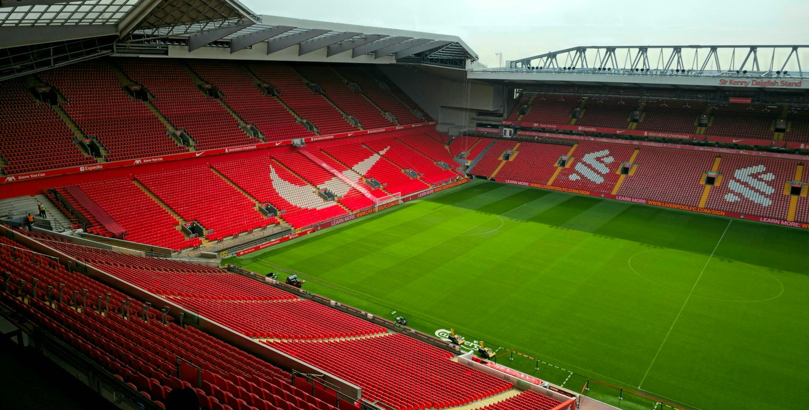 An empty stadium with red seats and green grass