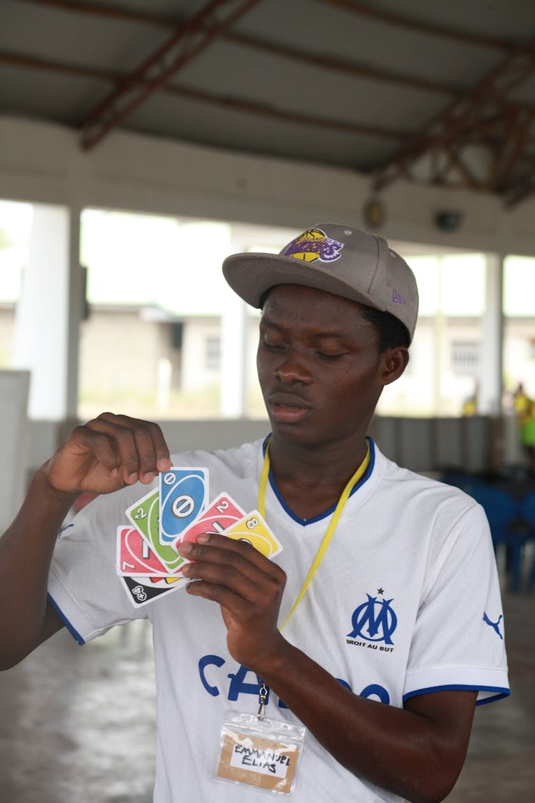 Man in Blue and White Shirt Playing Uno Cards